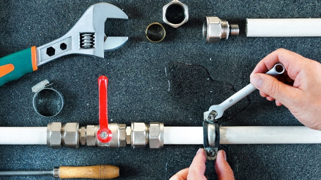 Plumber repairing a pipe valve with an adjustable wrench in La Quinta