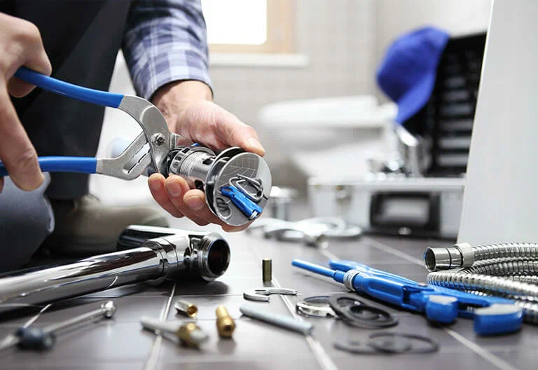 Technician repairing a plumbing fixture with professional tools in La Quinta