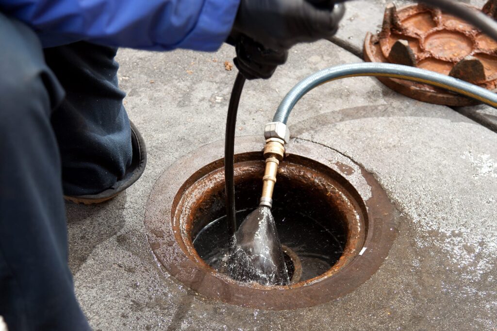 Plumber hydro jetting a sewer line through a manhole in La Quinta
