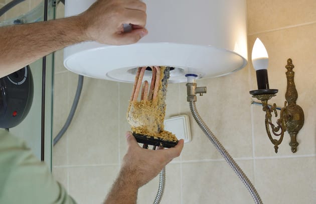Technician removing mineral buildup from a water heater in La Quinta
