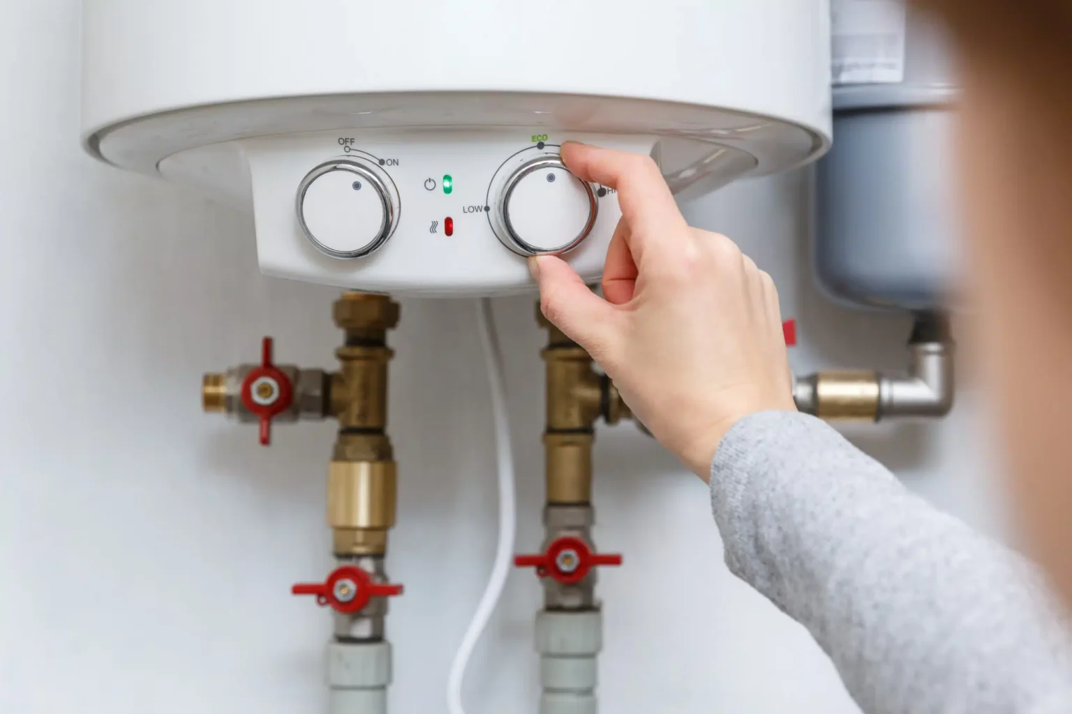 Homeowner adjusting the temperature controls on a water heater in La Quinta